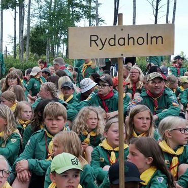 Bild på en stor grupp Uv-scouter bakom en skylt med texten Rydaholm