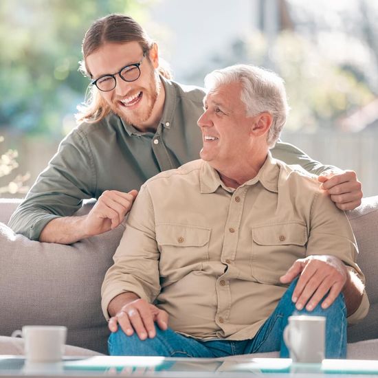 An adult son sitting with his elderly father