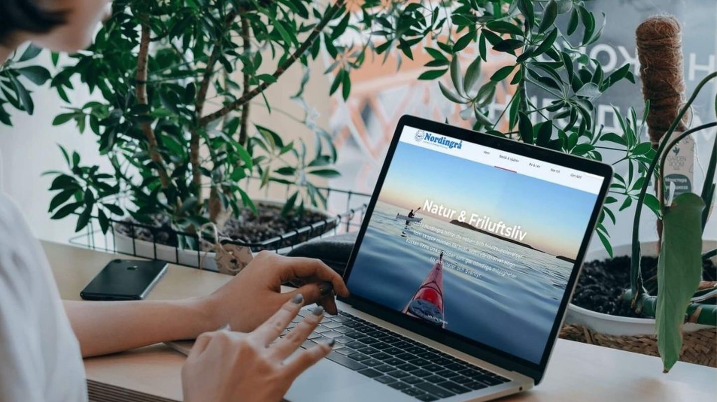 En kvinna med en laptop scrollar på Nordingrås nya hemsida