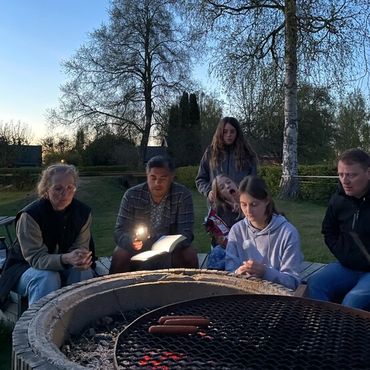 Bild på ungdomar runt en lägereld som läser en bibel