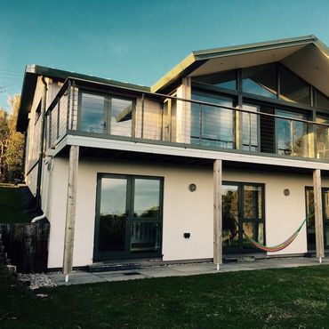 View of the back of the house looking up to the full width balcony with entrances to 3 of the 5 bedrooms in view below
