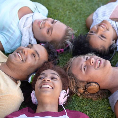 A group of students is lying on the lawn with their heads together