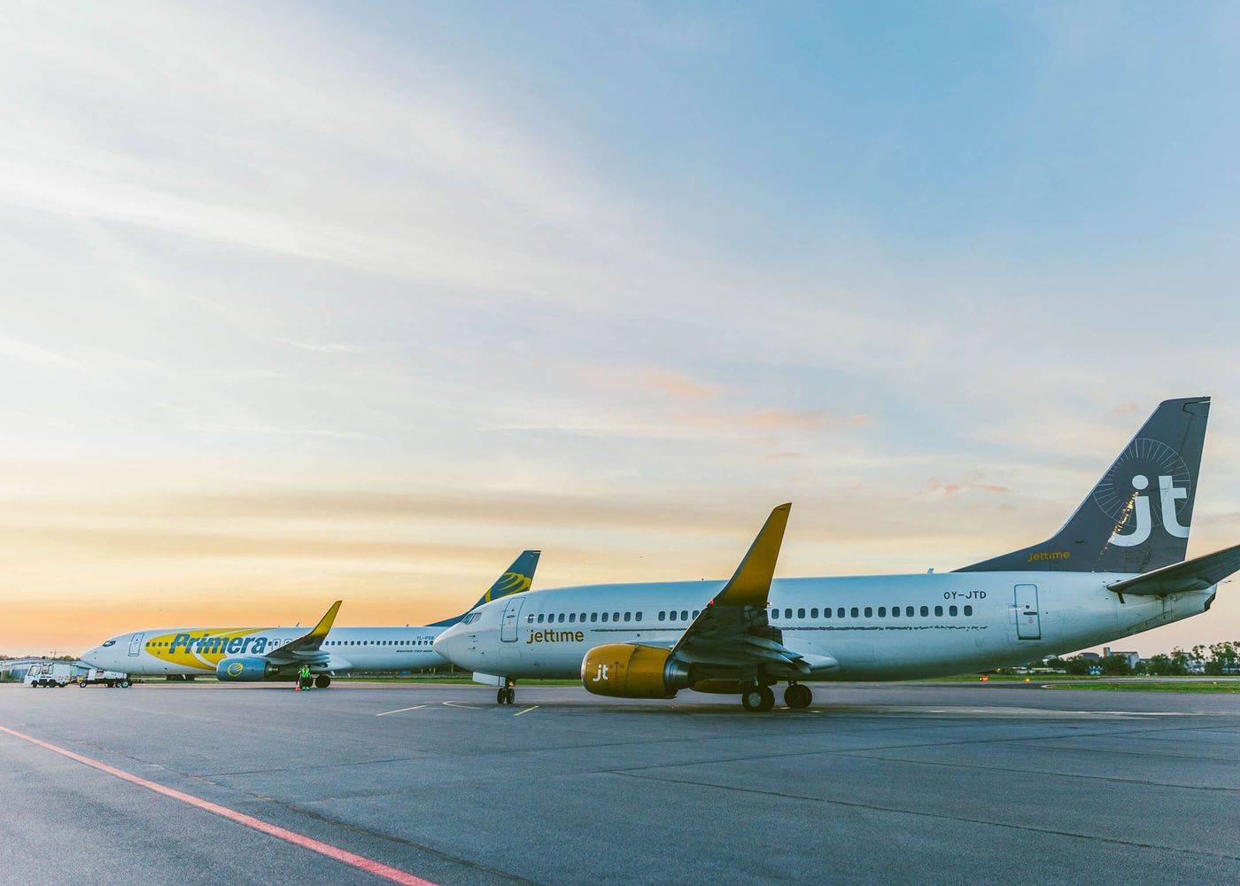 Två passagerarflygplan parkerade på flygplatsen i solnedgång