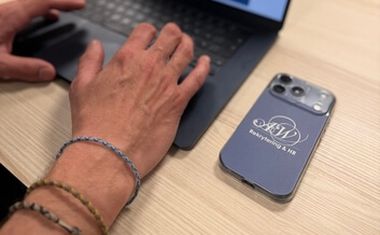 Hand som skriver på tangentbord med mobil på sidan