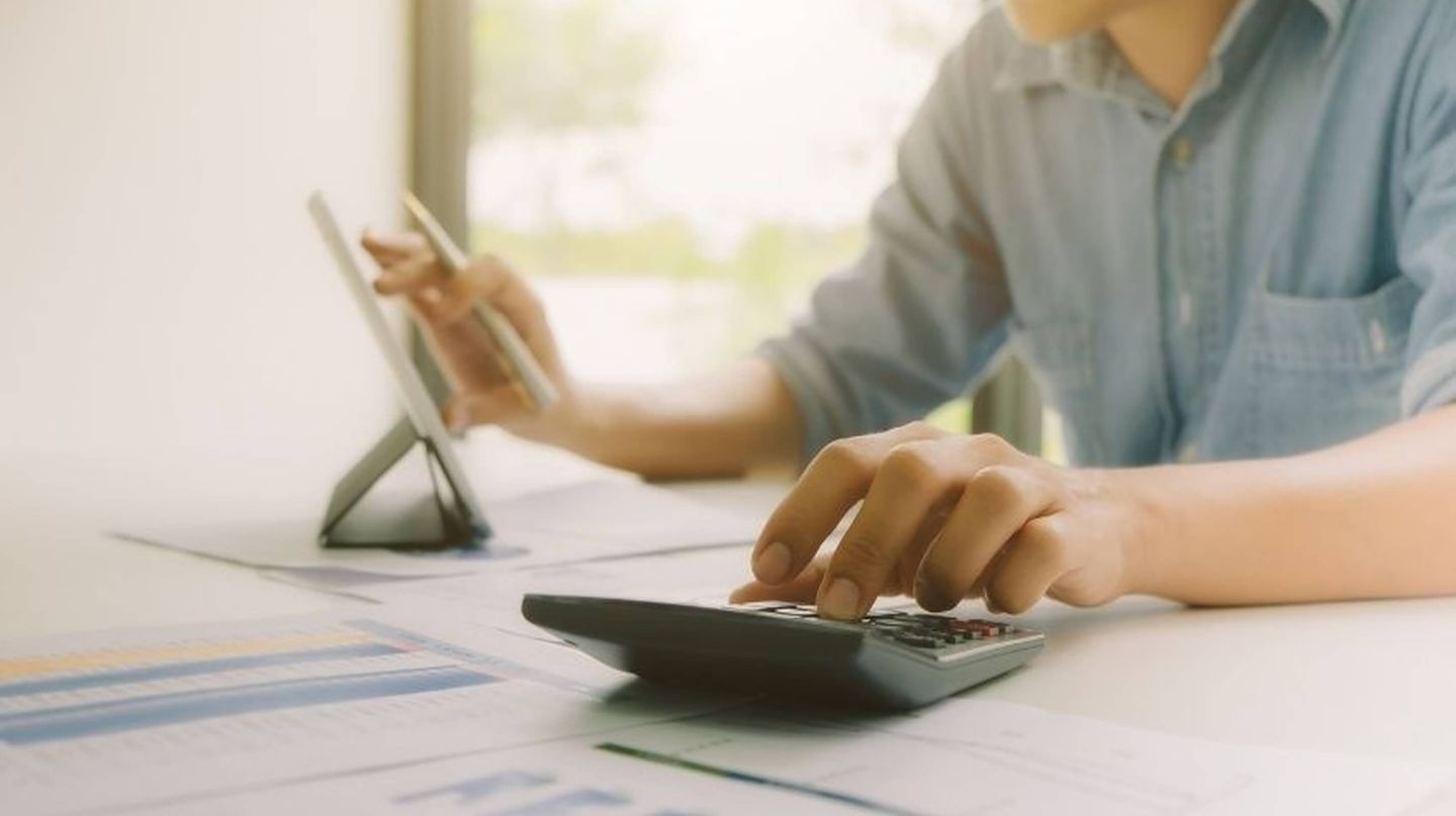 Man with a calculator in front of a tablet