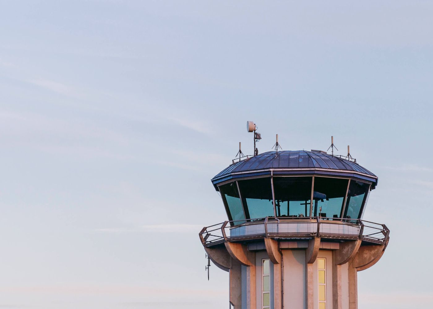 Flygplatstorn i betong och glas mot en ljus kvällshimmel