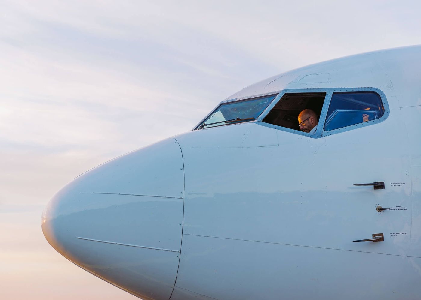 Pilot i cockpit på ett passagerarflygplan i solnedgångsljus