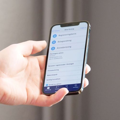 En hand som håller i en smartphone. Bolagsverkets app syns på skärmen