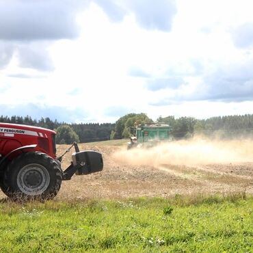 Spridning av strukturkalk på en åker med en traktor i förgrunden