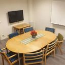Interiör från konferensrummet Utvik i Generationernas hus i Ullånger. Bilden visar ett bord med 8 stolar, en whiteboard och en TV