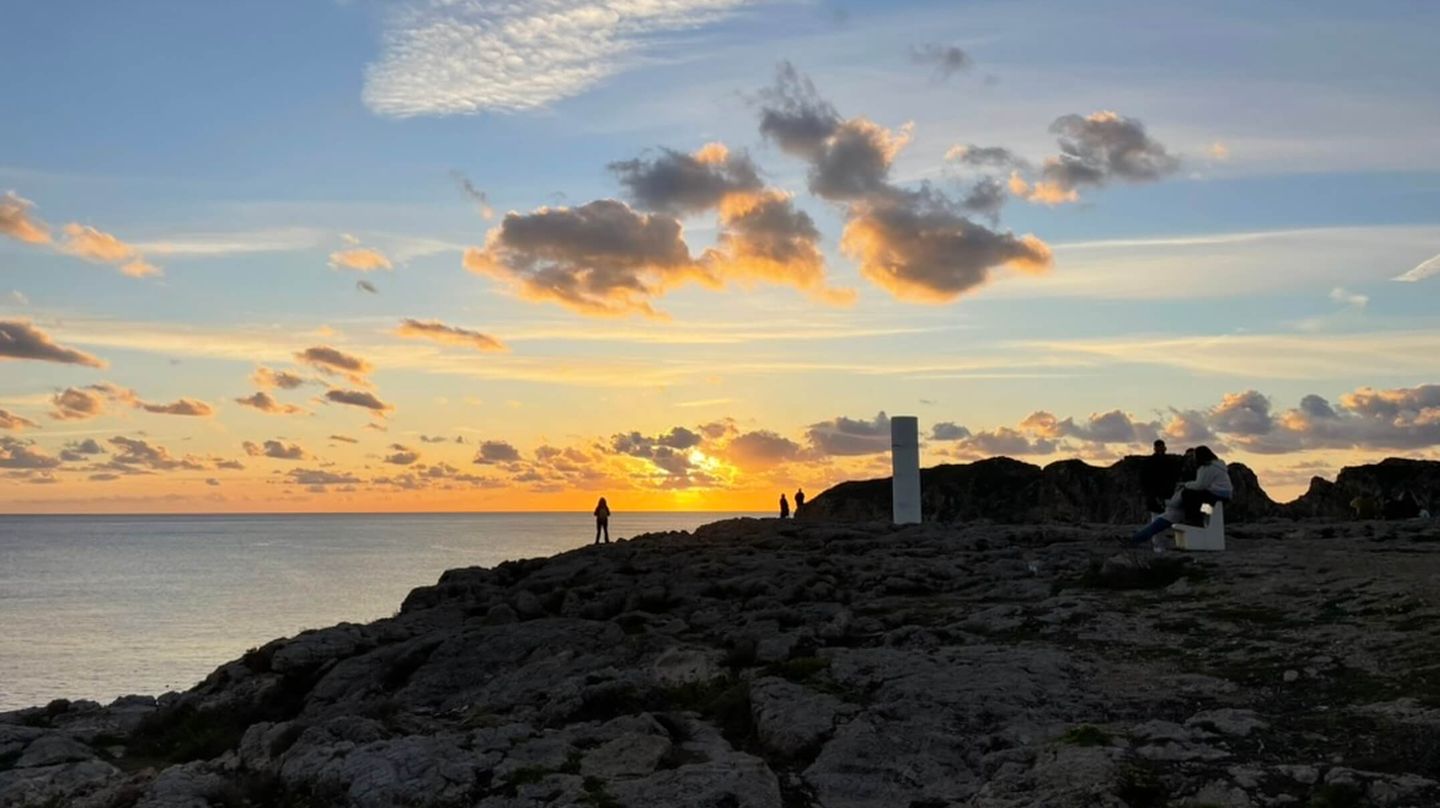 Sol, hav och klippor med avlägsna människor