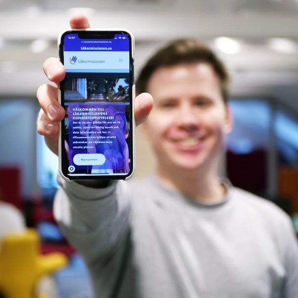 En person som håller upp en telefon som visar en hemsida producerad av Beegleton