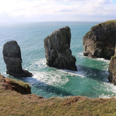Stack Rocks (or Elegug Stacks) are two dramatic, 25-meter-high limestone pillars near Castlemartin, Pembrokeshire, Wales, formed by coastal erosion and now a major seabird nesting site.