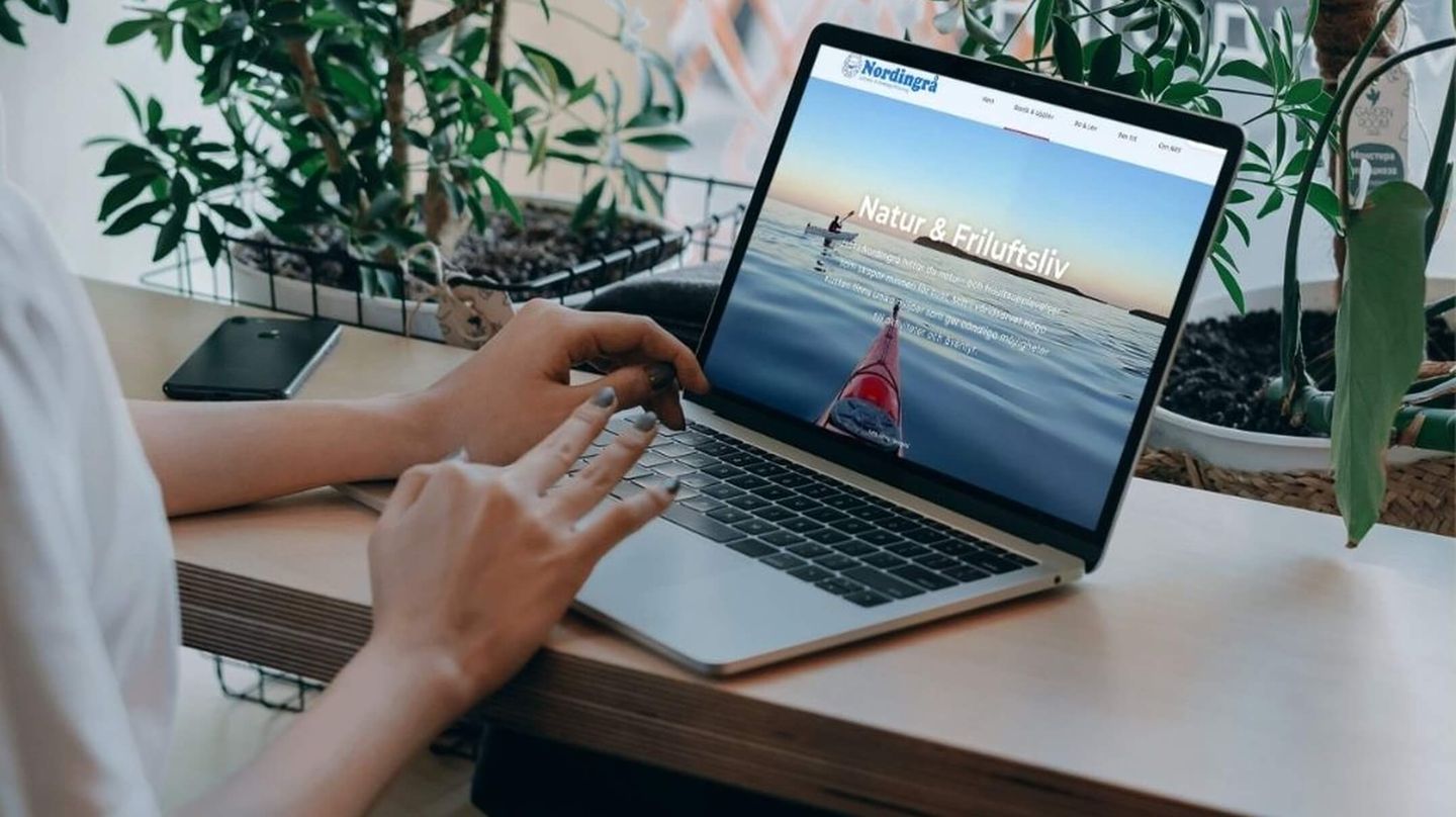 Kvinna som surfar på en laptop och kikar på Nordingrås nya hemsida