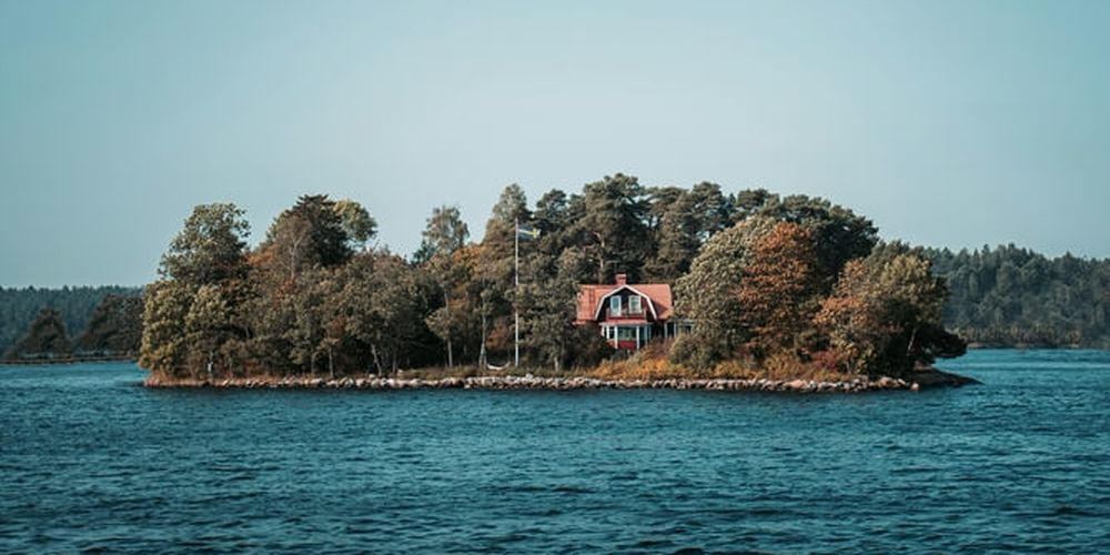 En röd stuga på en ö omgiven av vatten