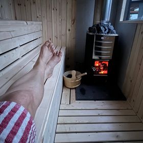Image of Harvia woodburning sauna stove with someone relaxing on the lower bench of our mobile sauna