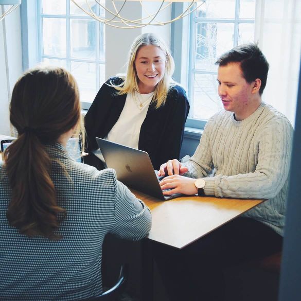 Tre personer framför en dator som jobbar med marknadsföring och reklam