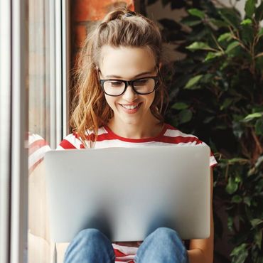 Kvinna sitter vid ett fönster med en laptop