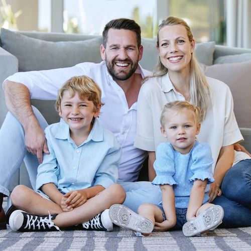 Eine glückliche Familie sitzt vor dem Sofa