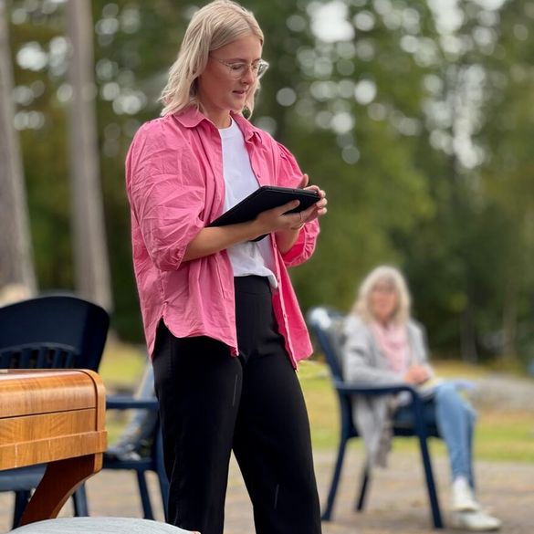 Bild på en kvinna som läser bibeln ute med person som lyssnar